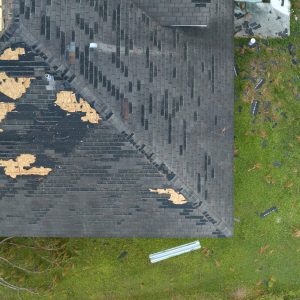Ruined rooftop in need of repair. Wind damaged house roof with missing asphalt shingles after hurricane Ian in Florida.