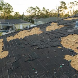 Ruined rooftop in need of repair. Wind damaged house roof with missing asphalt shingles after hurricane Ian in Florida.