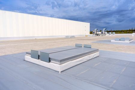 White metal sheet rooftop wall on commercial building with blue sky.